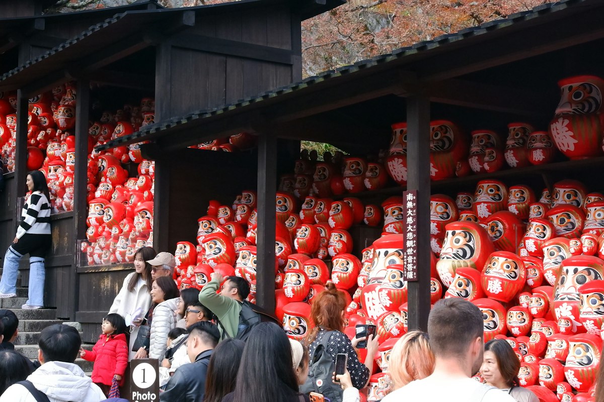 Những búp bê daruma màu đỏ bày trước một ngôi nhà truyền thống