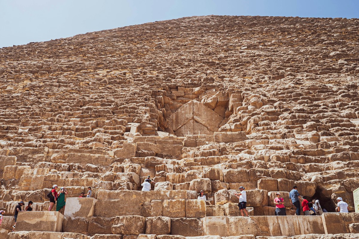 Du khách đứng trên bức tường đá cổ trước một công trình lớn ở Giza