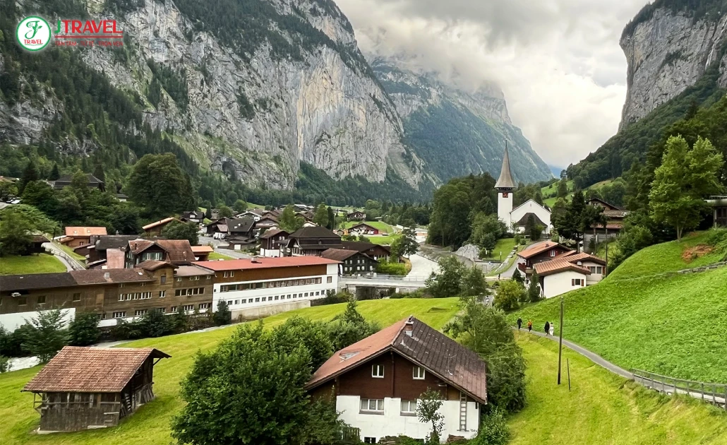 Khung cảnh làng Lauterbrunnen Thụy Sĩ với những ngôi nhà gỗ cổ kính và cánh đồng xanh giữa thung lũng