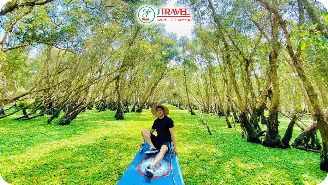 Du khách ngồi trên xuồng di chuyển xuyên qua rừng tràm