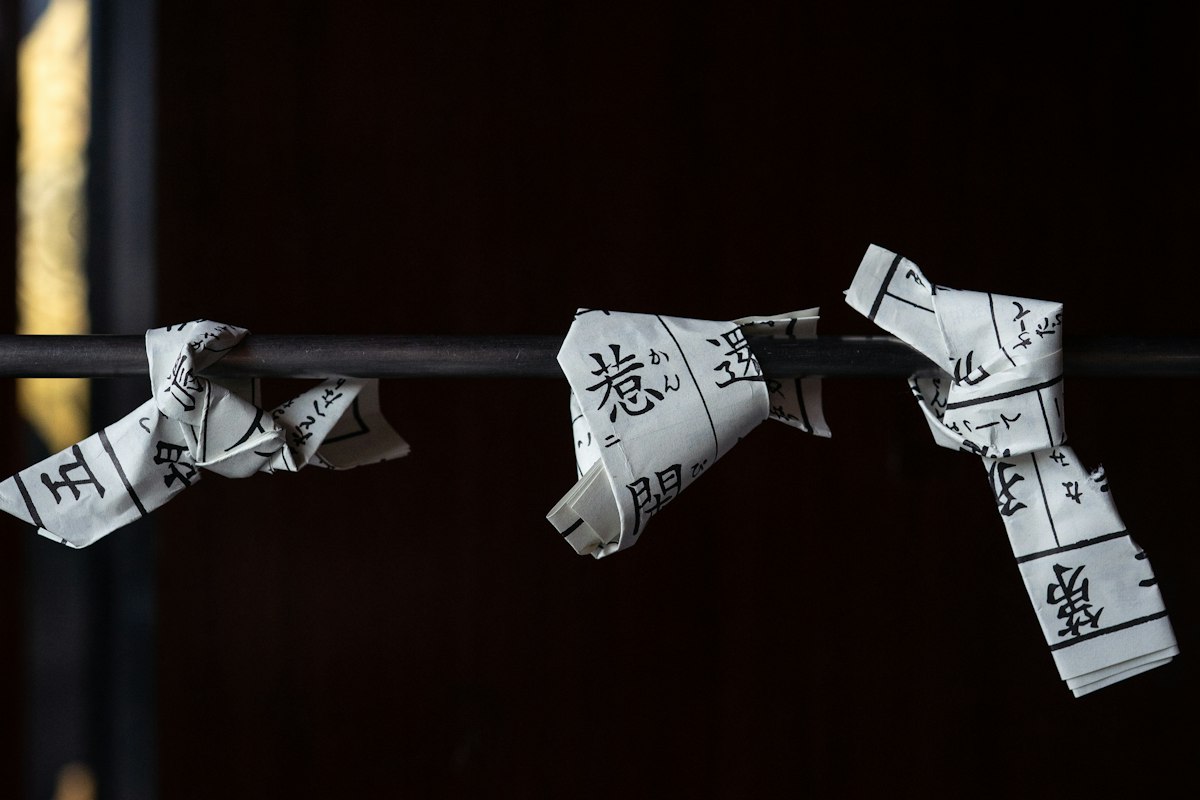 Những quẻ giấy omikuji được buộc thành hàng tại một ngôi đền Nhật Bản