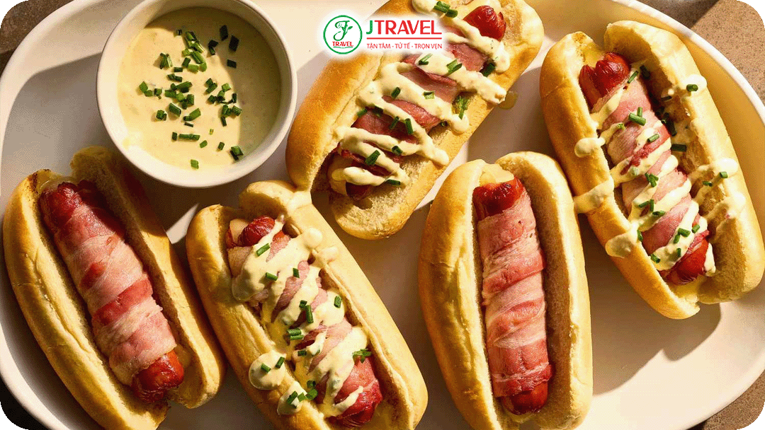 Xúc xích được nướng hoặc luộc, kẹp trong bánh mì dài, ăn kèm mù tạt, dưa muối