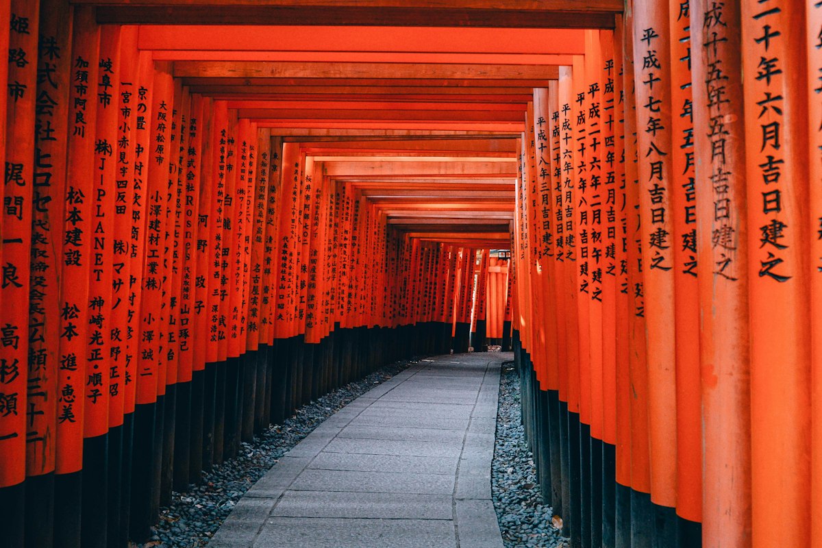 Lối đi lát đá giữa hai hàng cột torii đỏ và đen